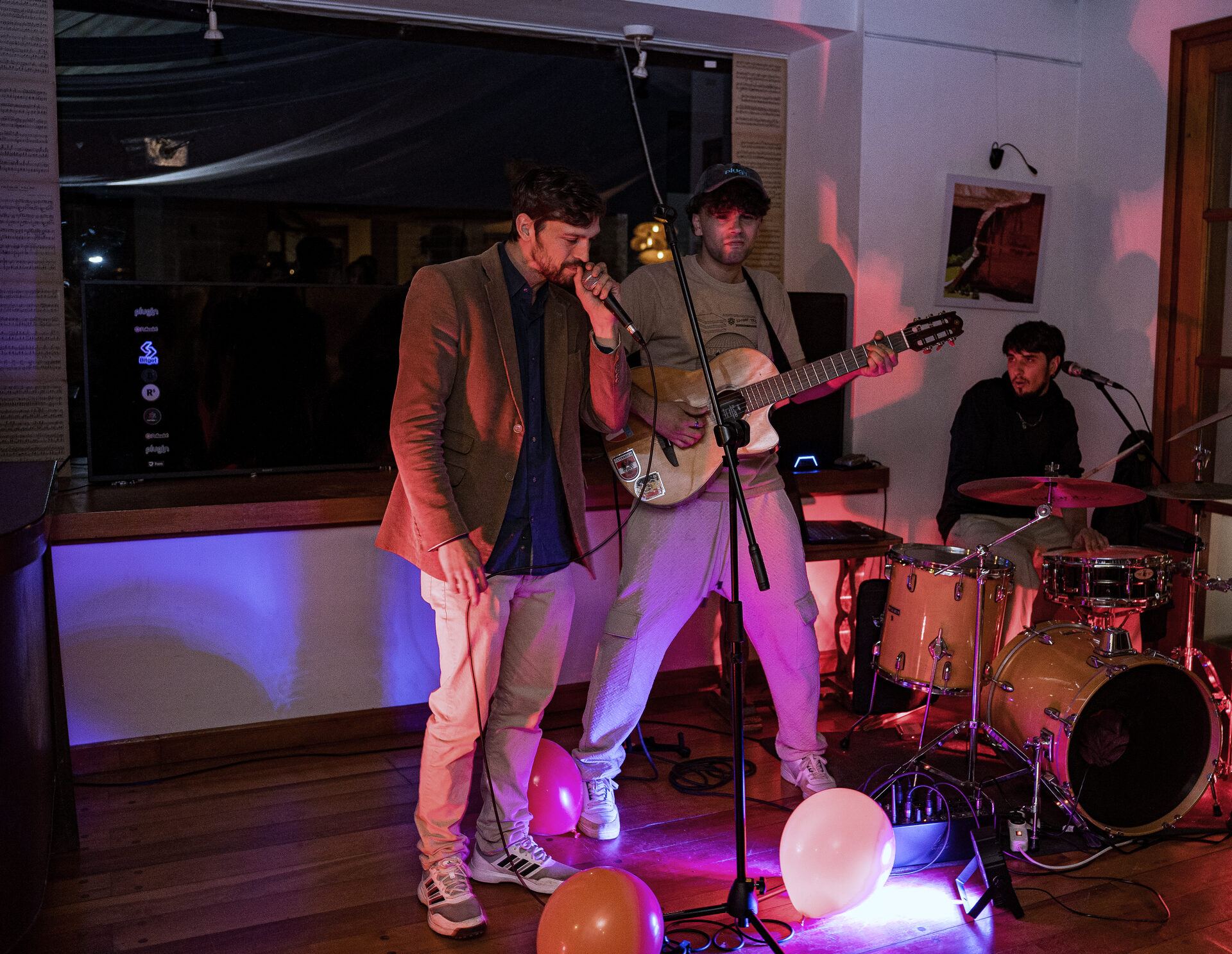 A live band with vocals, guitar and drums on stage.