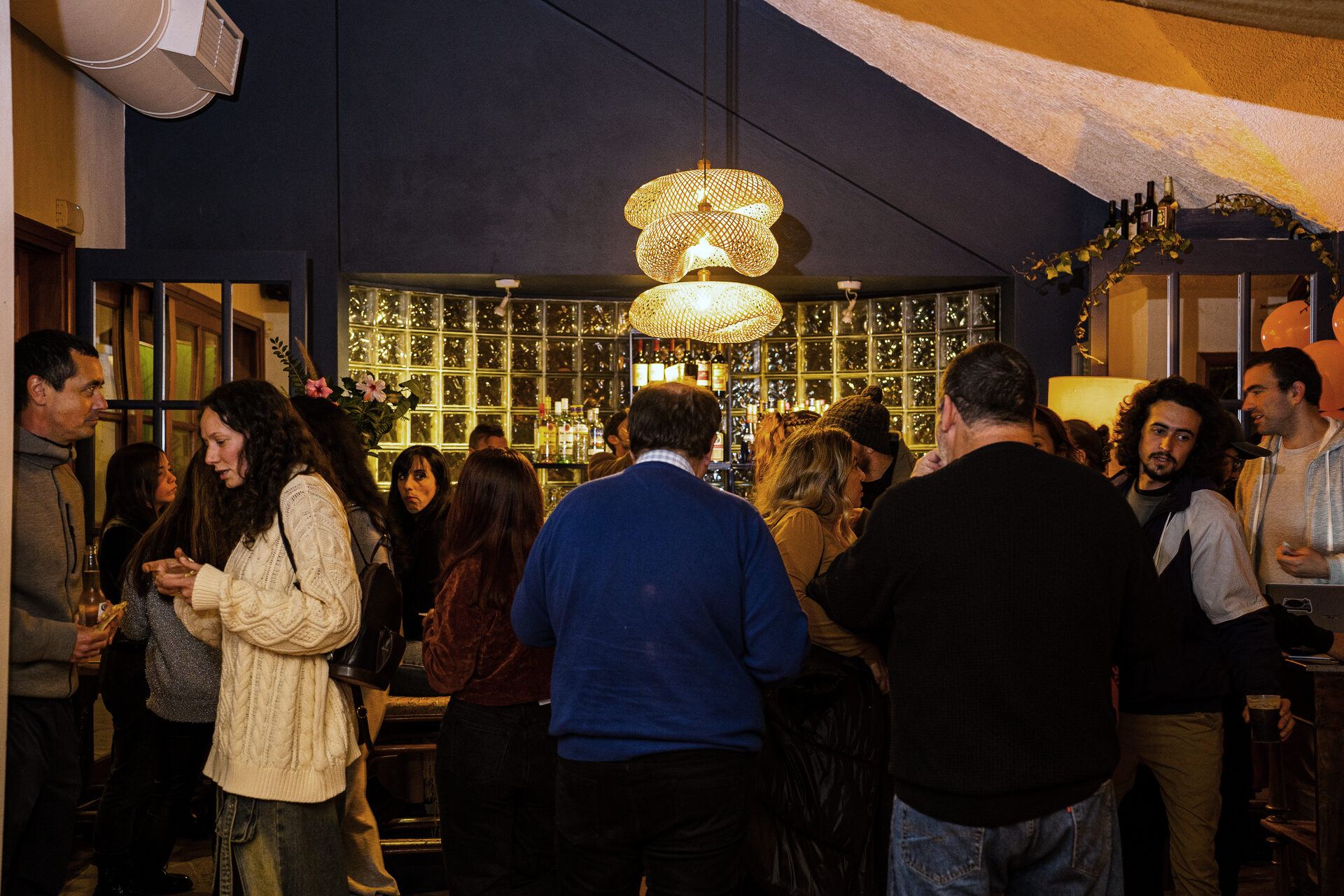 A group of guests standing at the lit bar of the venue.
