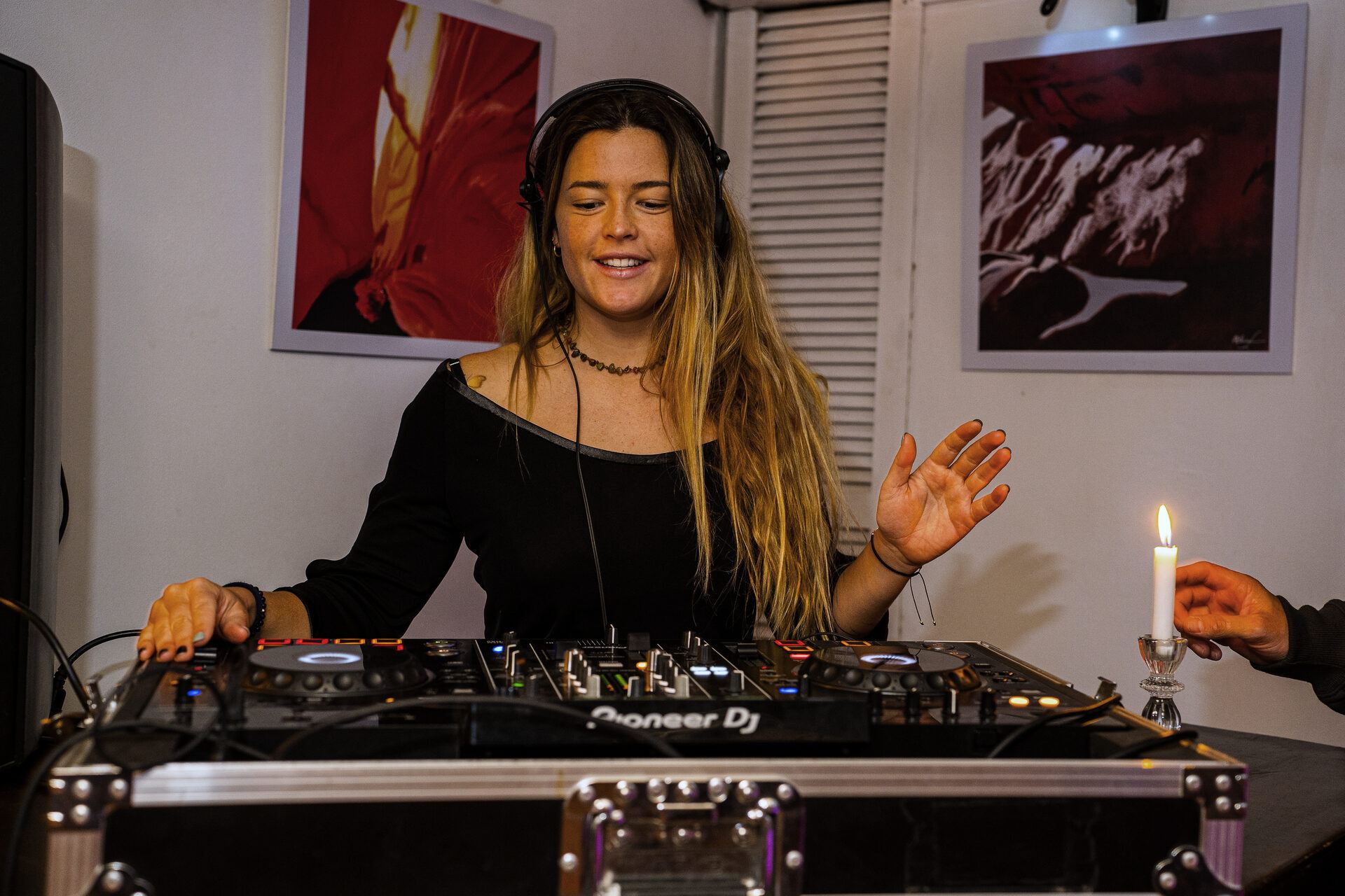 A DJ mixing at the booth next to a lit candle.