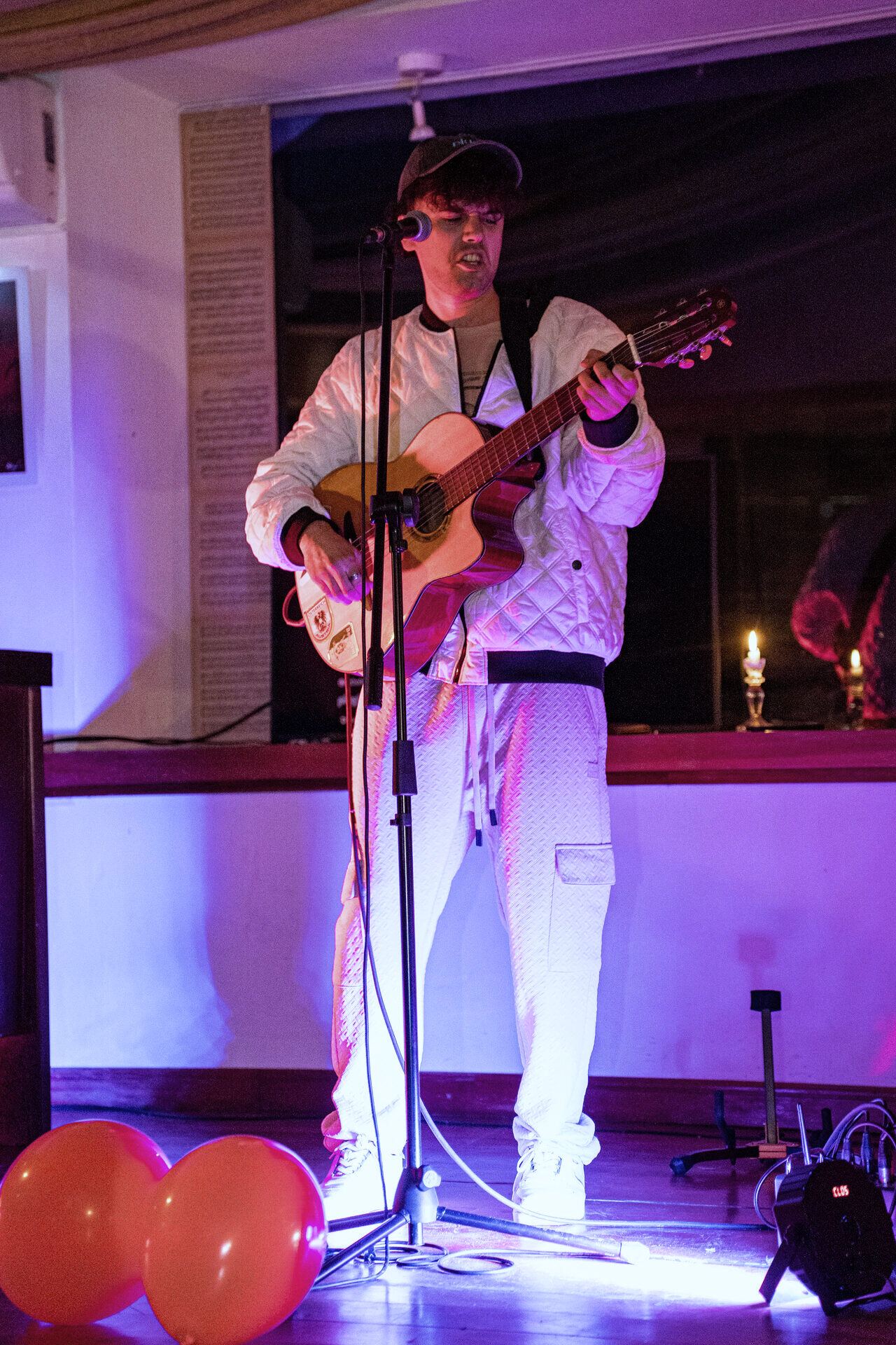 A guitarist playing live under magenta and violet lights.