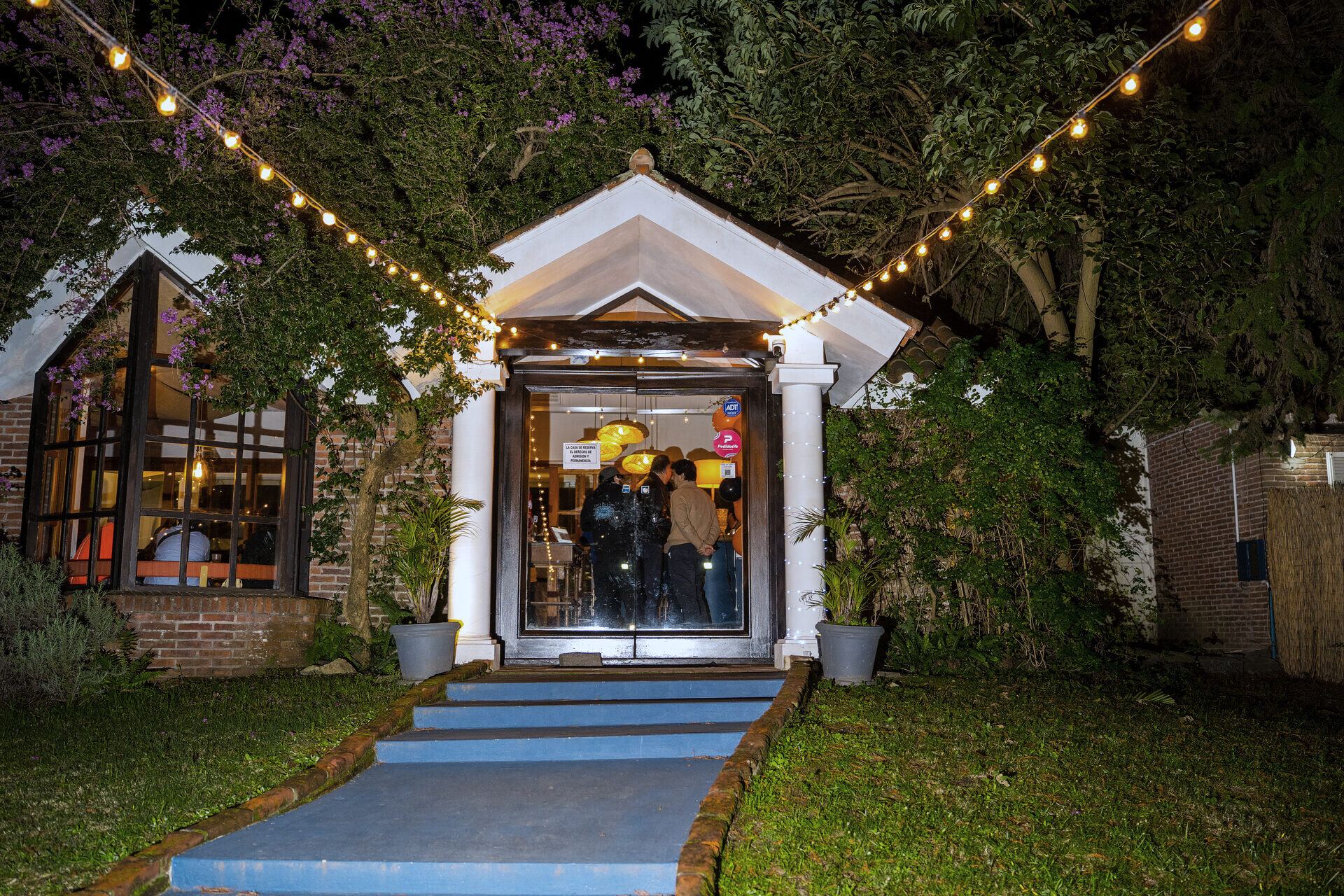 Entrance path lit by strings of bulbs leading to the doorway at night.